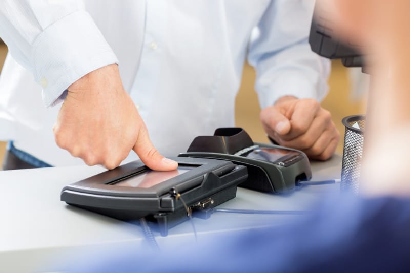 Customer Giving Thumb Impression To Make Payment In Pharmacy